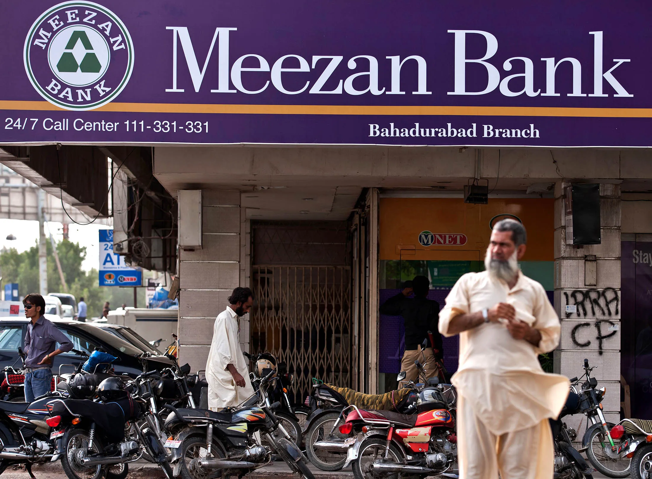 Pedestrians pass in front of a branch of the Meezan Bank in Karachi.
