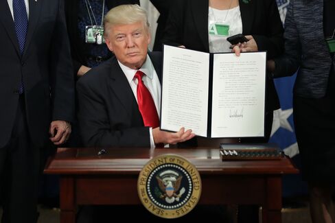 国土安全保障省で署名した大統領令を掲げるトランプ氏 (25日)