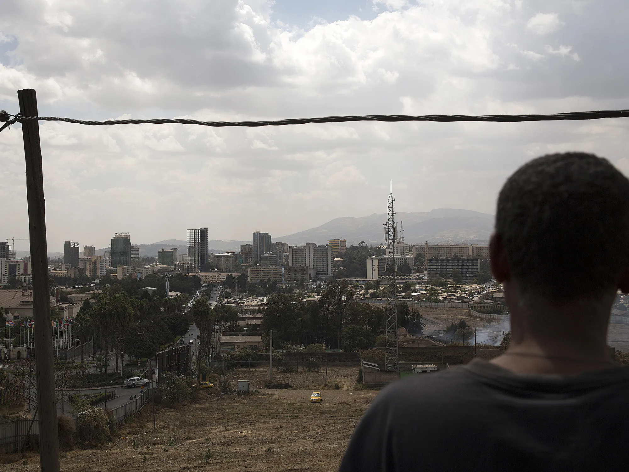 A pedestrian looks out over commercial and residential buildings on the city skyline in Addis Ababa, Ethiopia.