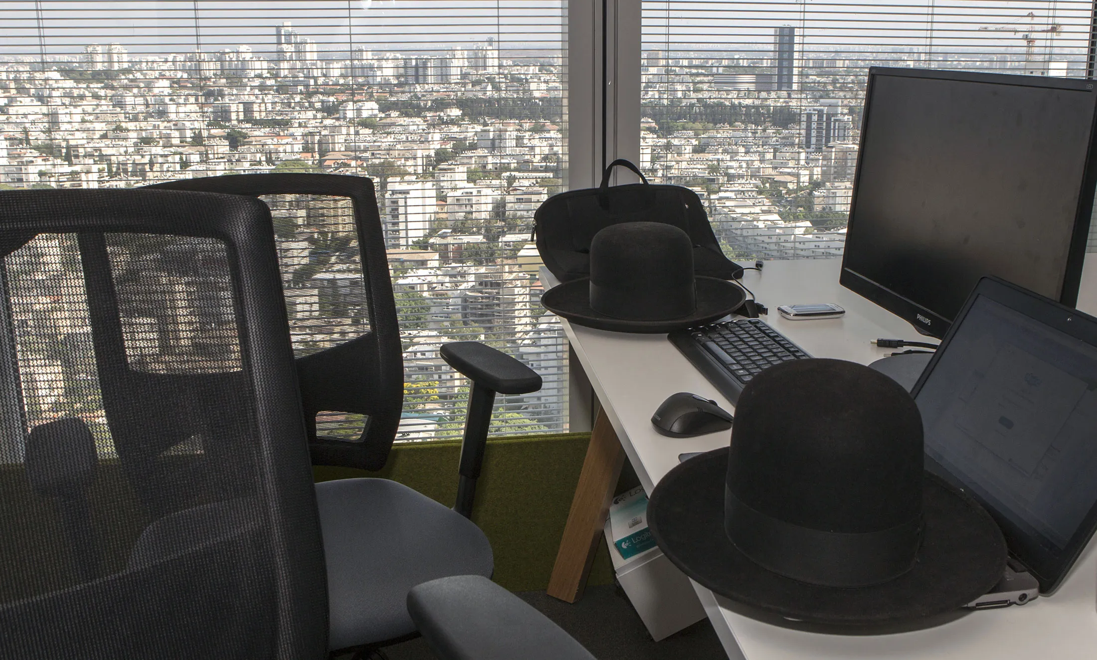 The hats of haredi ultra-Orthodox jews sit on computer desks at a tech startup office.

