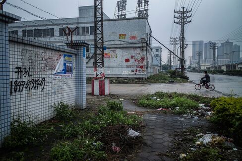A man rides a bicycle at an abandoned industrial area in Dongguan, China. The country set a range for its economic growth target for the first time in two decades,The new goal comes at a precarious time as policy makers battle the slowest growth in 25 years, the yuan dropping to a five-year low and the second bear market in stocks in less than a year.