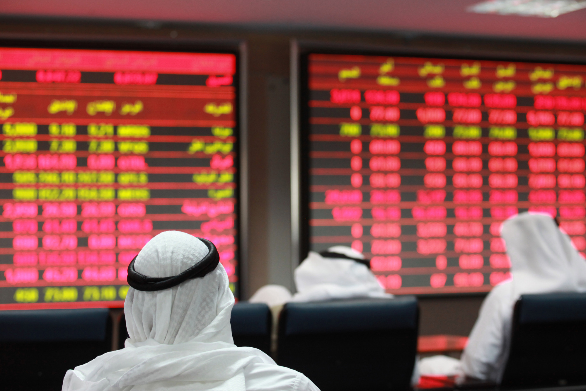 Visitors look at financial information screens on display inside the Qatar Exchange in Doha, Qatar.