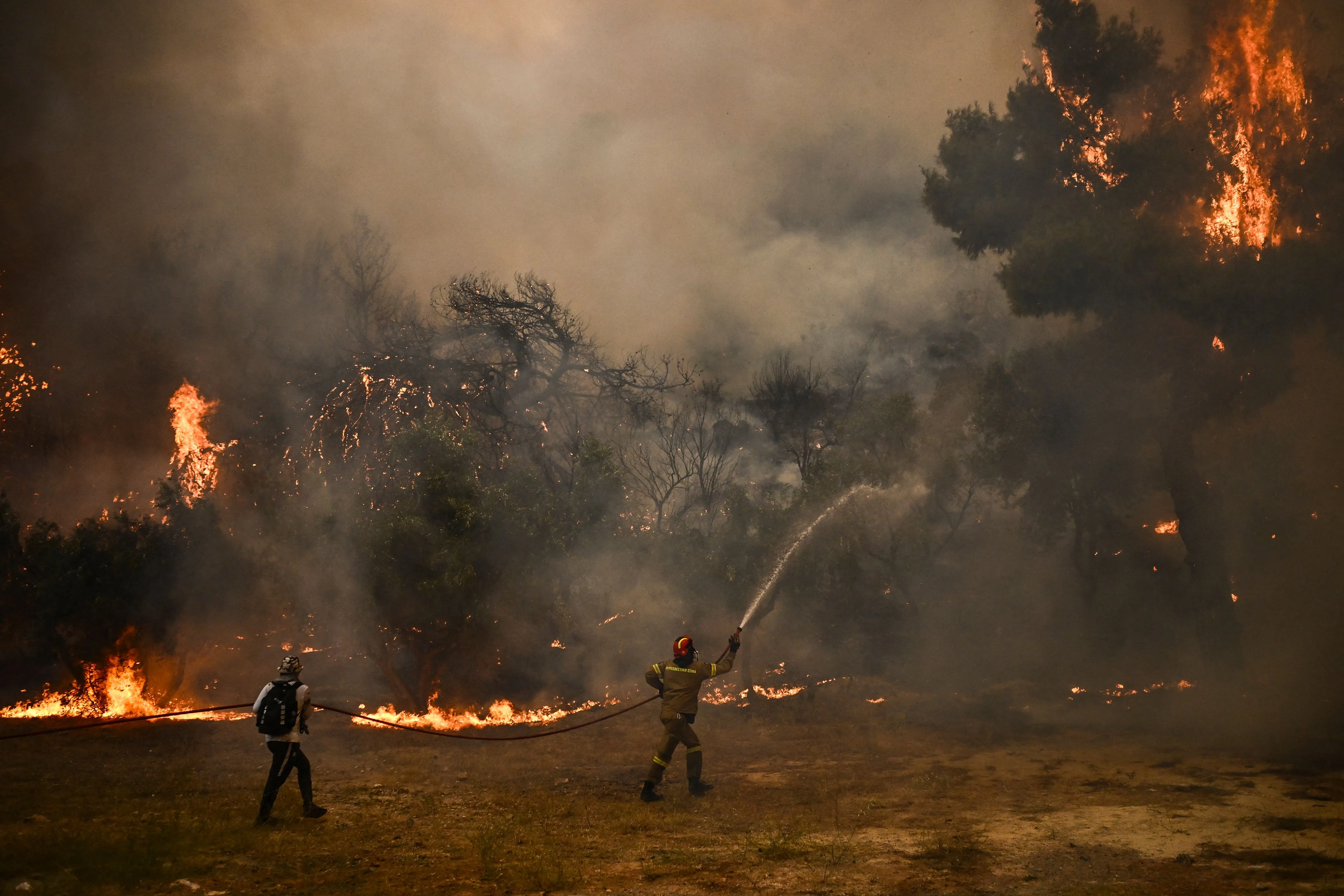 &nbsp;A firefighter sprays water on the flames during a wildfire in Chasia, Greece&nbsp;in Aug. 2023.