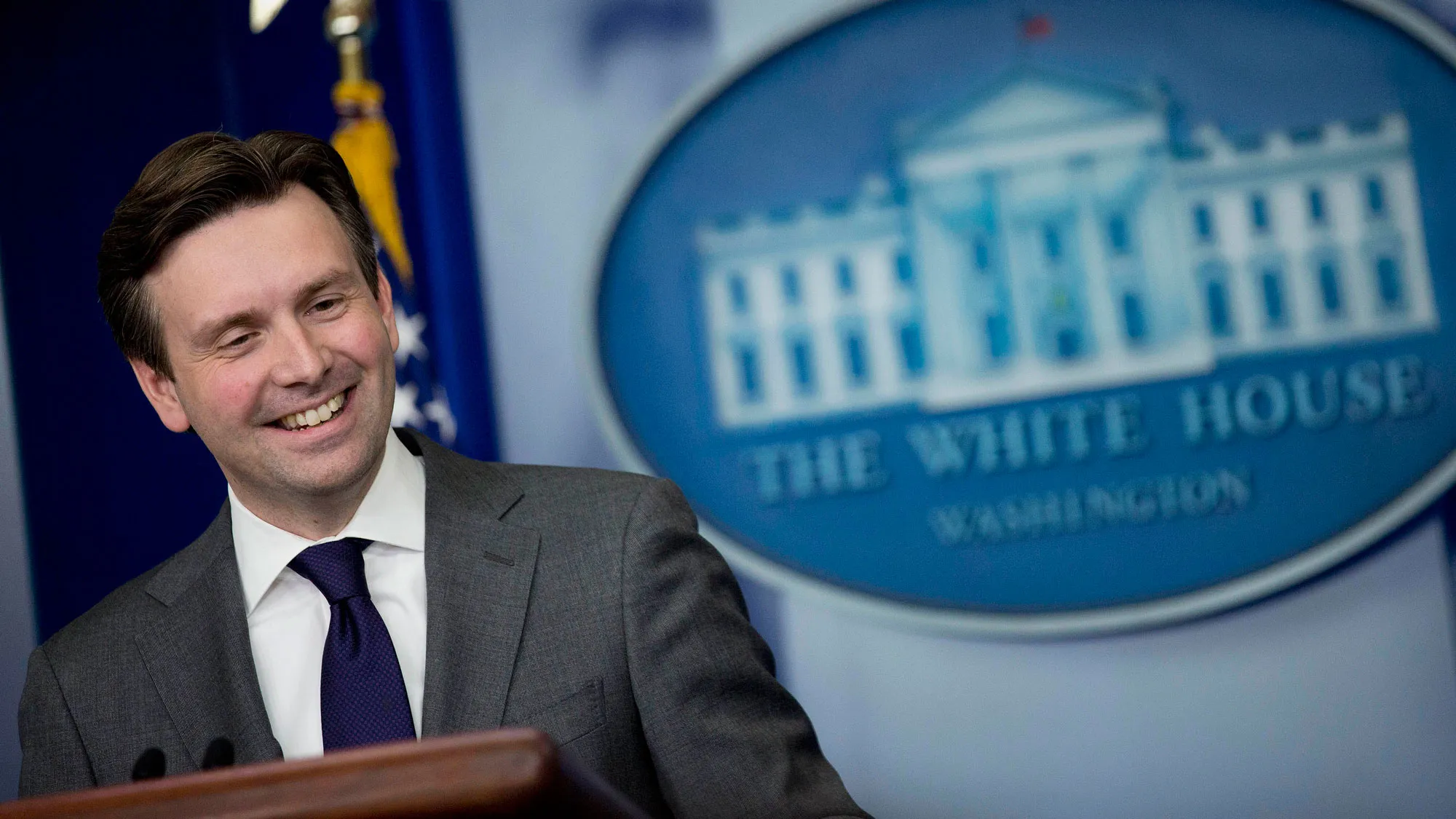 osh Earnest, White House press secretary, smiles during a press briefing at the White House in Washington, D.C., U.S., on Thursday, Dec. 18, 2014.
