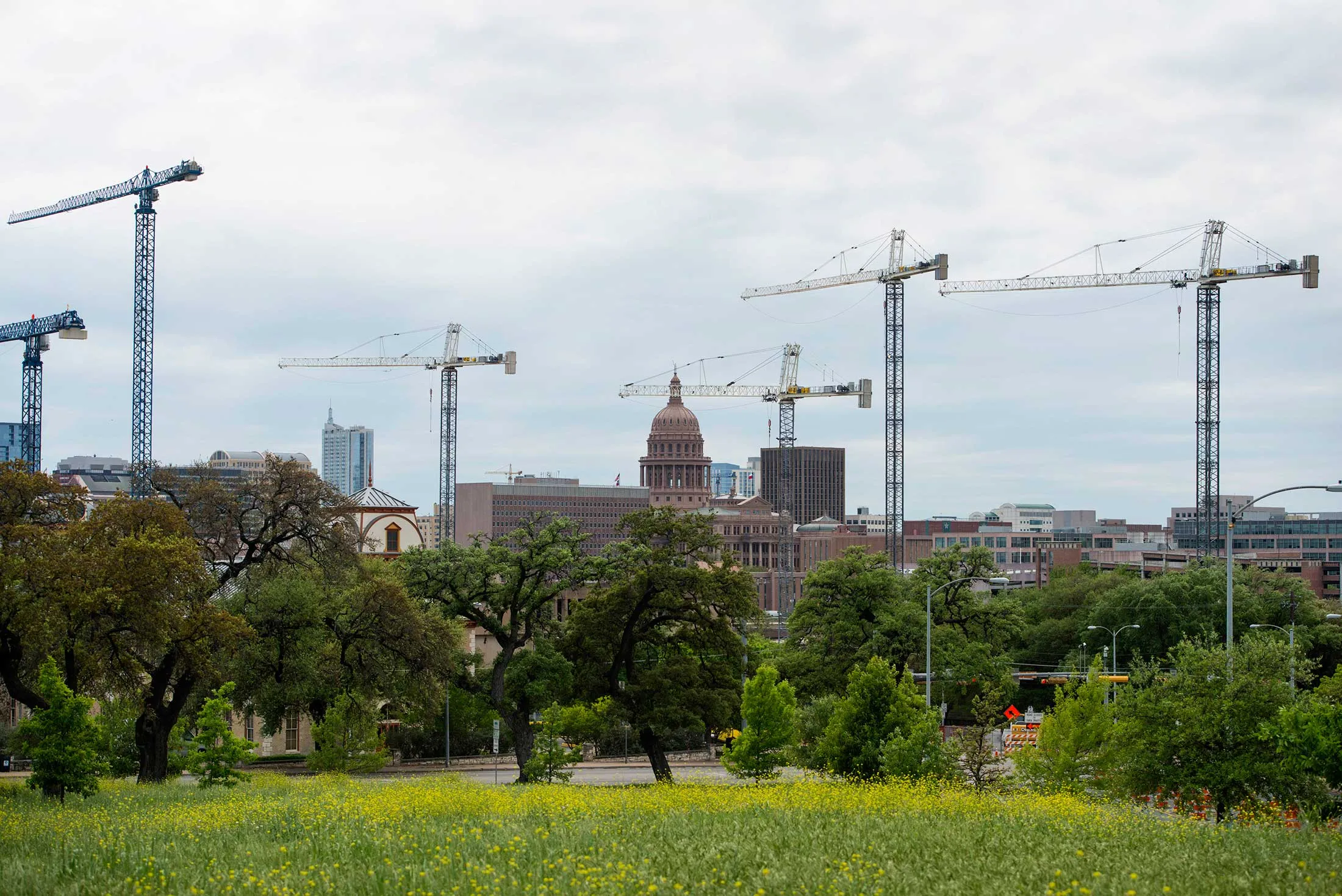 The Texas State Capitol building stands beyond construction cranes at the University of Texas at Austin campus in Austin, Texas, on April 4, 2015. About 900,000 people live in the city of Austin and that number is expected to reach nearly 1.3 million by 2040, a 40 percent increase, according to city figures. More than 100 people move to the city a day, according to the city's demographer.
