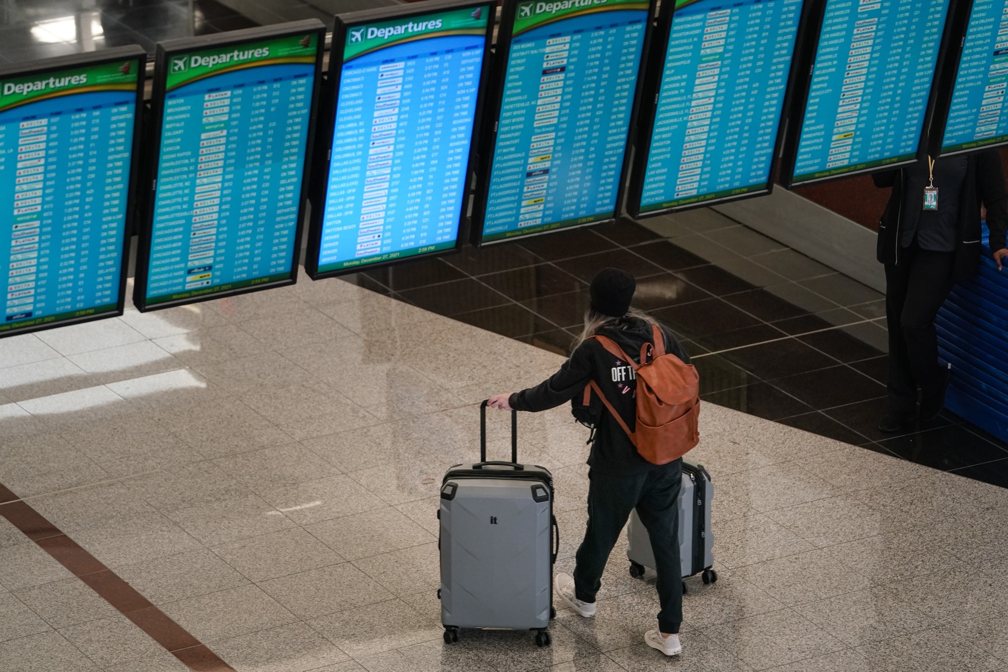 A traveler passes under a row of departure boards at Hartsfield-Jackson Atlanta International Airport.
