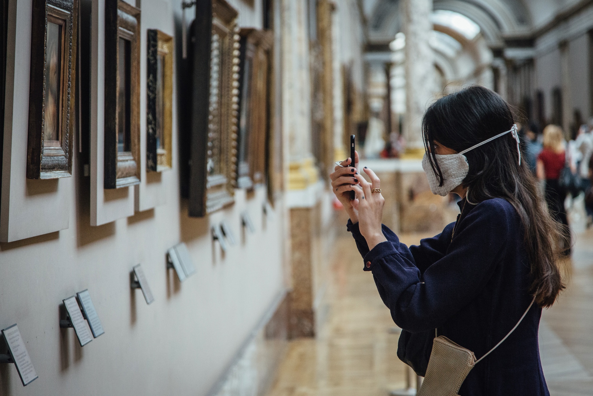 A visitor wearing a protective face mask takes a photograph of paintings in the Louvre Museum in Paris, France, on&nbsp;July 6.&nbsp;