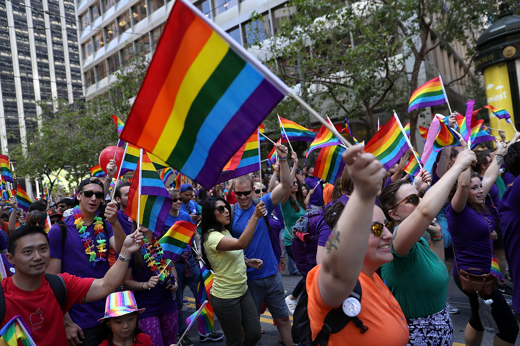 Parade participants wave pride flags as the march during the 2016 San Francisco Pride Parade on June 26, 2016.