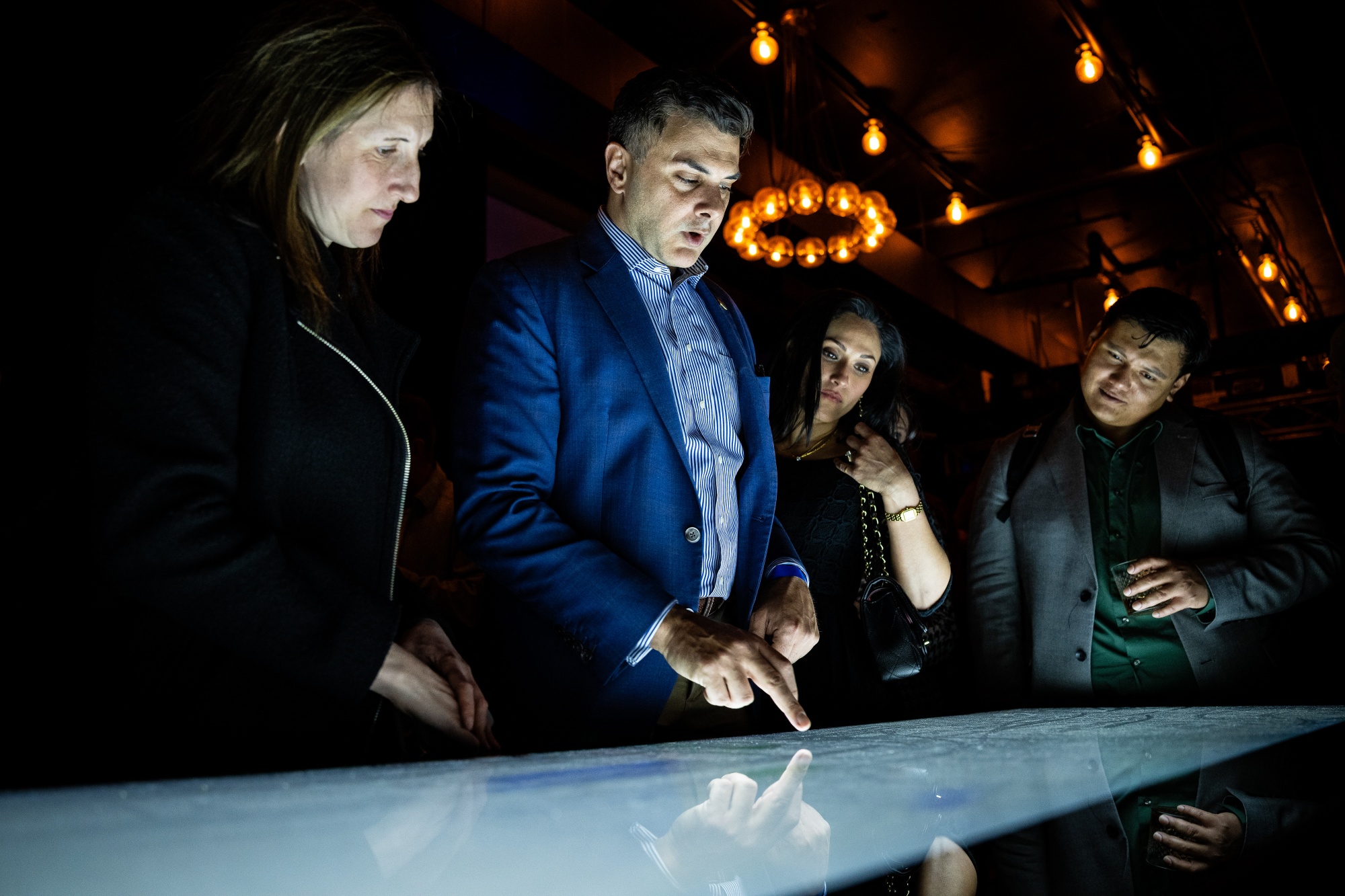 Neal Kumar, chief legal officer of Polymarket, center left, uses an electronic Polymarket display during the opening of The Situation Room by Polymarket pop-up bar in Washington, DC, US, on Friday, March 20, 2026. Polymarket took over a bar near the White House, for a promotional event showcasing the prediction market’s vision of betting on current events as a new form of entertainment. Photographer: Graeme Sloan/Bloomberg