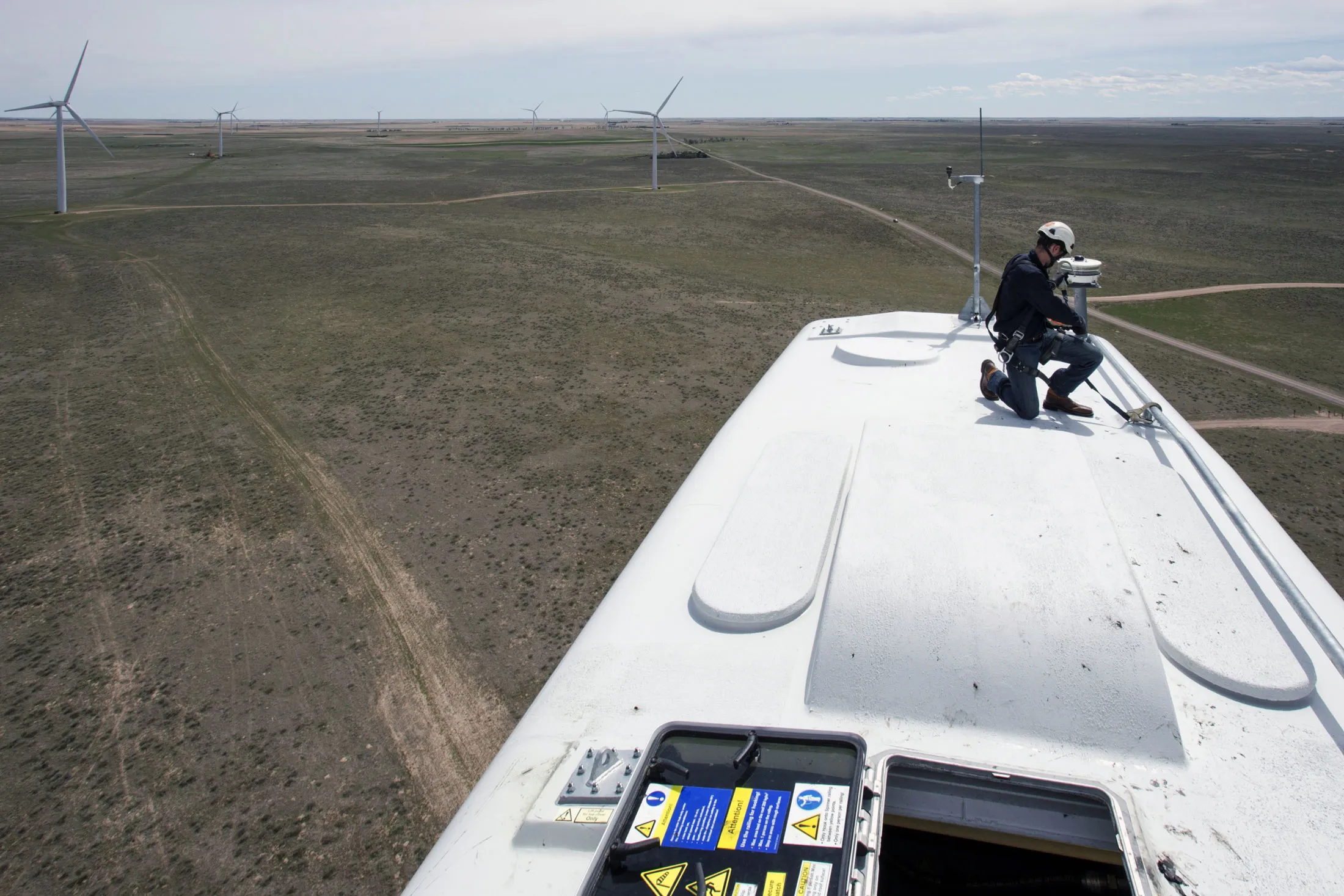 A General Electric Co. renewable energy technician kneels on a turbine at the Colorado Highlands Wind Farm in Fleming, Colorado.