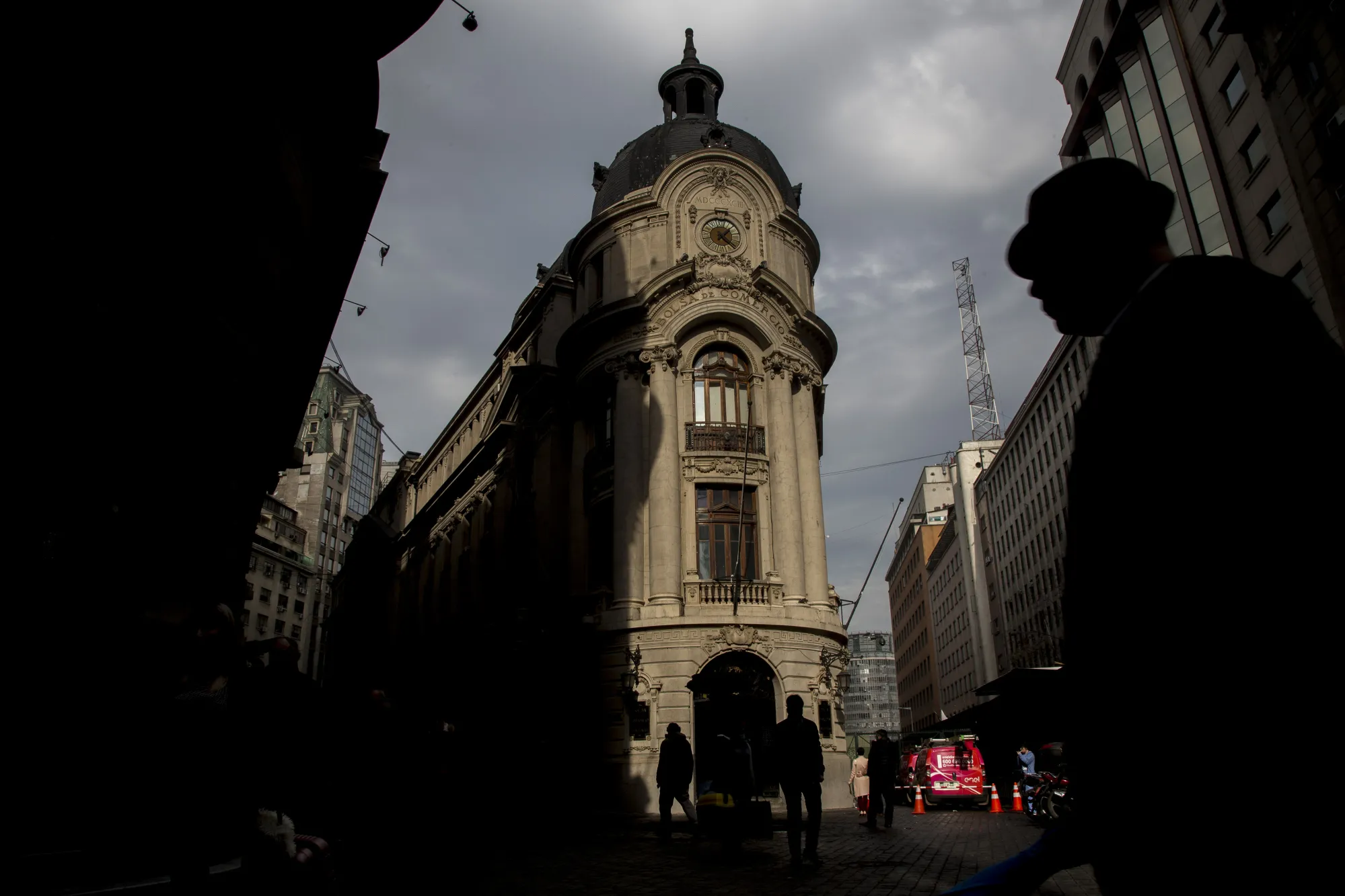 The silhouettes of pedestrians are seen passing in front of the Santiago Stock Exchange in Santiago.