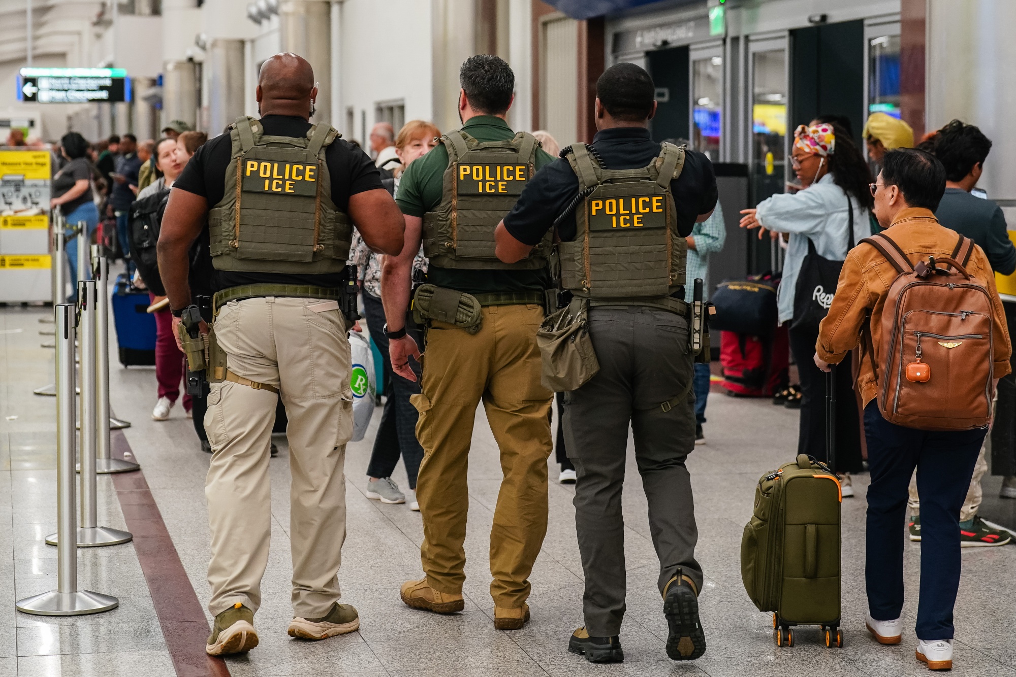Immigration and Customs Enforcement (ICE) agents as travelers wait in line to be screened at a Transportation Security Administration (TSA) checkpoint at Hartsfield-Jackson Atlanta International Airport (ATL) in Atlanta, Georgia, US, on Monday, March 23, 2026. President Donald Trump said he's ready to deploy Immigration and Customs Enforcement agents to US airports as soon as Monday if congressional Democrats dont agree to a plan for funding parts of the Department of Homeland Security. Photographer: Elijah Nouvelage/Bloomberg