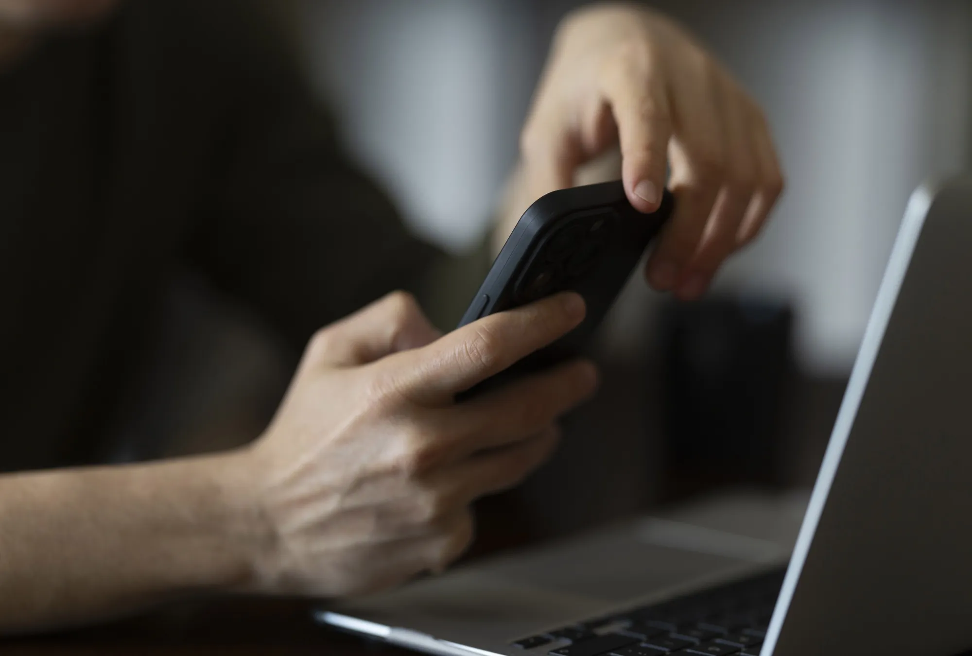 Close up of hands using smartphone and laptop computer