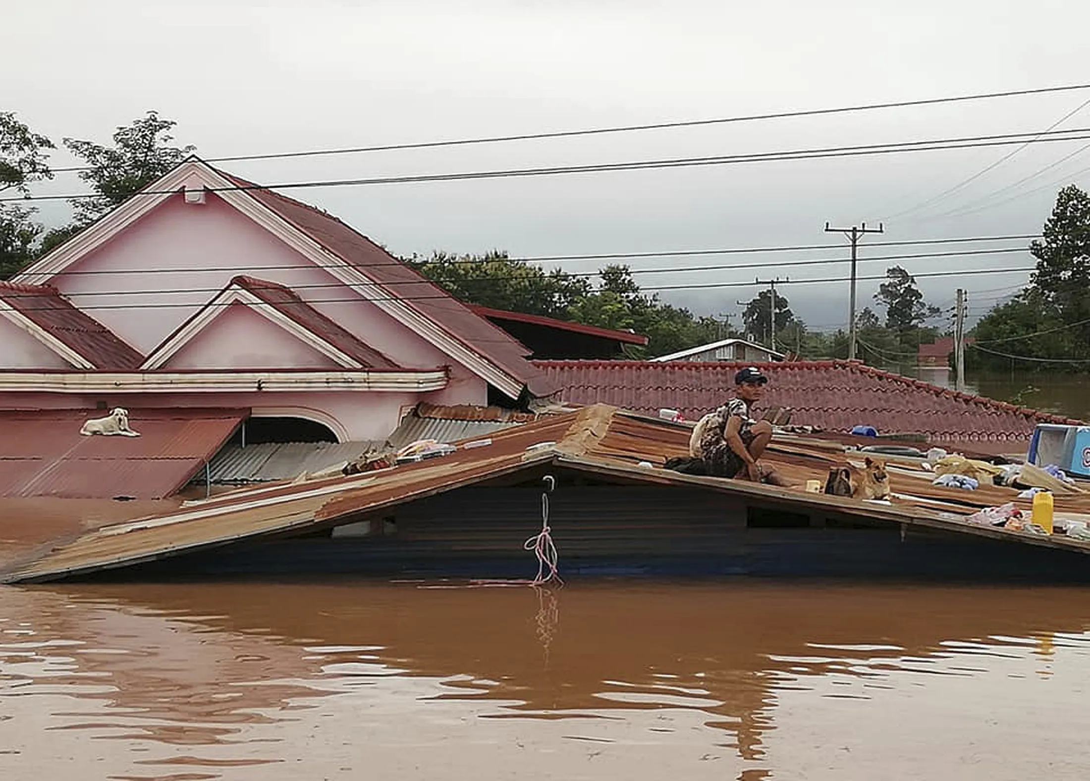 A villager takes refuge on a rooftop above flood waters from a collapsed dam on July 24, 2018.