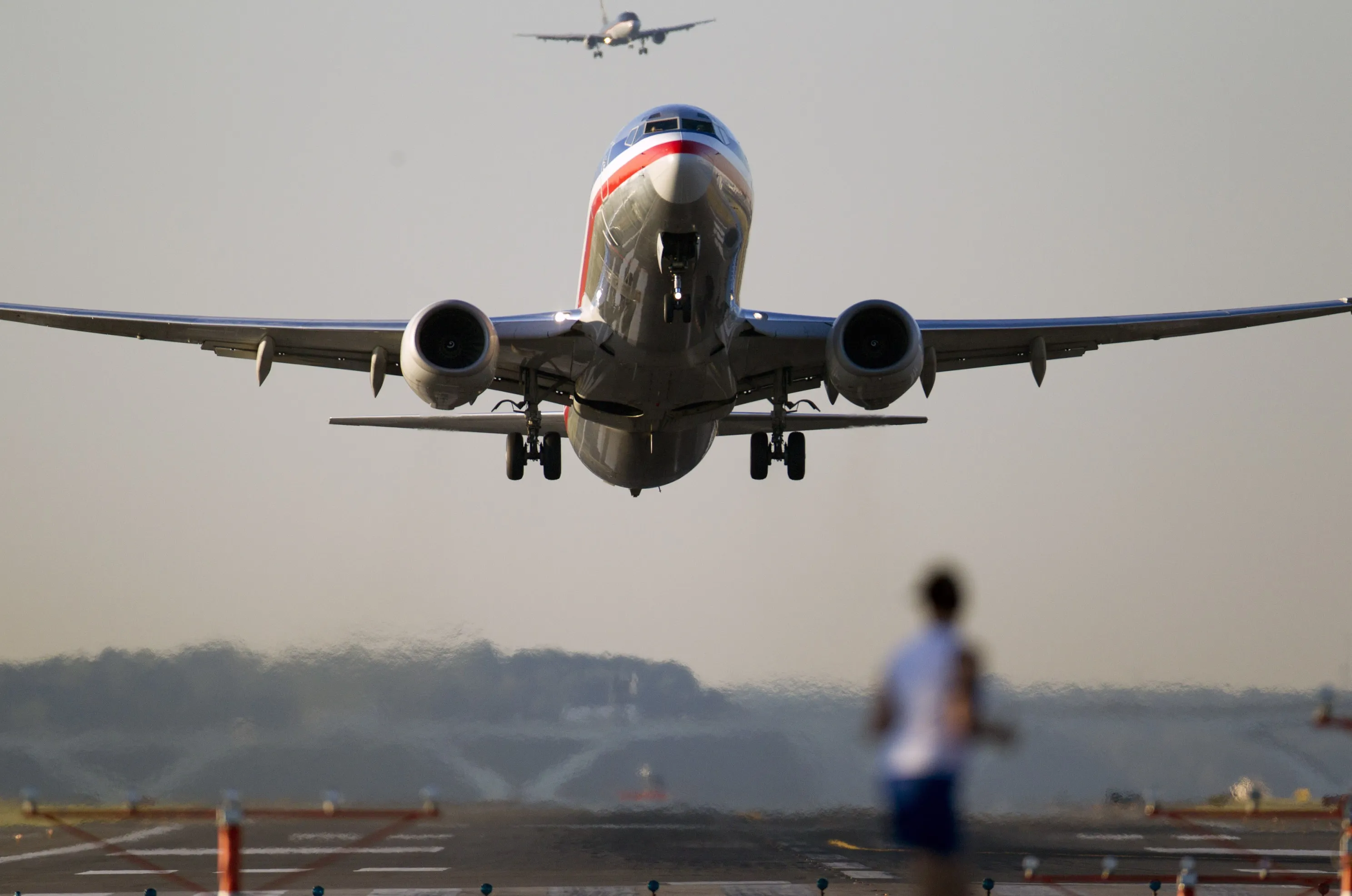 A runner looks on as an American Airlines Boeing Co. 737 jet takes off at Ronald Reagan National Airport in Arlington, Virginia.