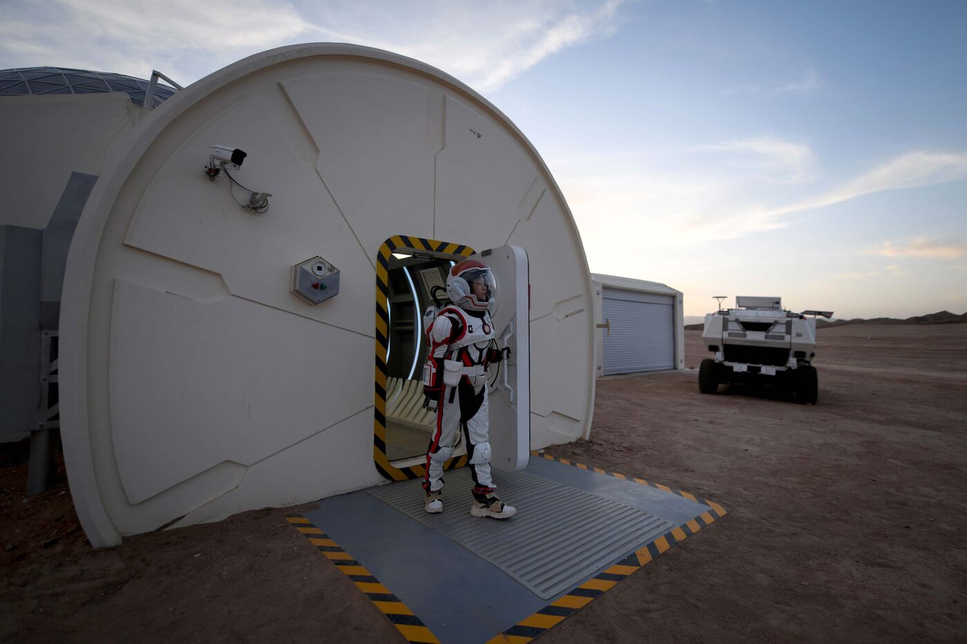 A woman wearing a simulation spacesuit walks out of Mars Base 1.