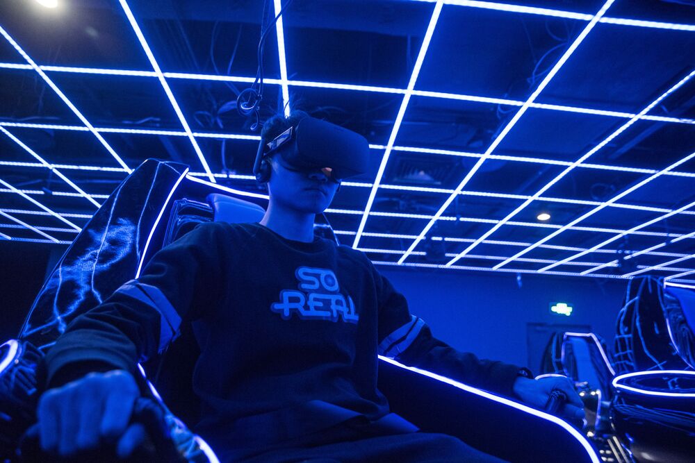 An employee wears a virtual reality (VR) headset while demonstrating a 4D cinema that can accommodate 23 people at the SoReal virtual reality park in Beijing, China.