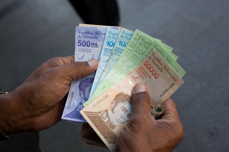 A person holds a new 500,000 bolivar banknote beside old 10,000, 20,000 and 50,000 bolivar banknotes outside a bank in Caracas, Venezuela, on Monday, March 15, 2021.