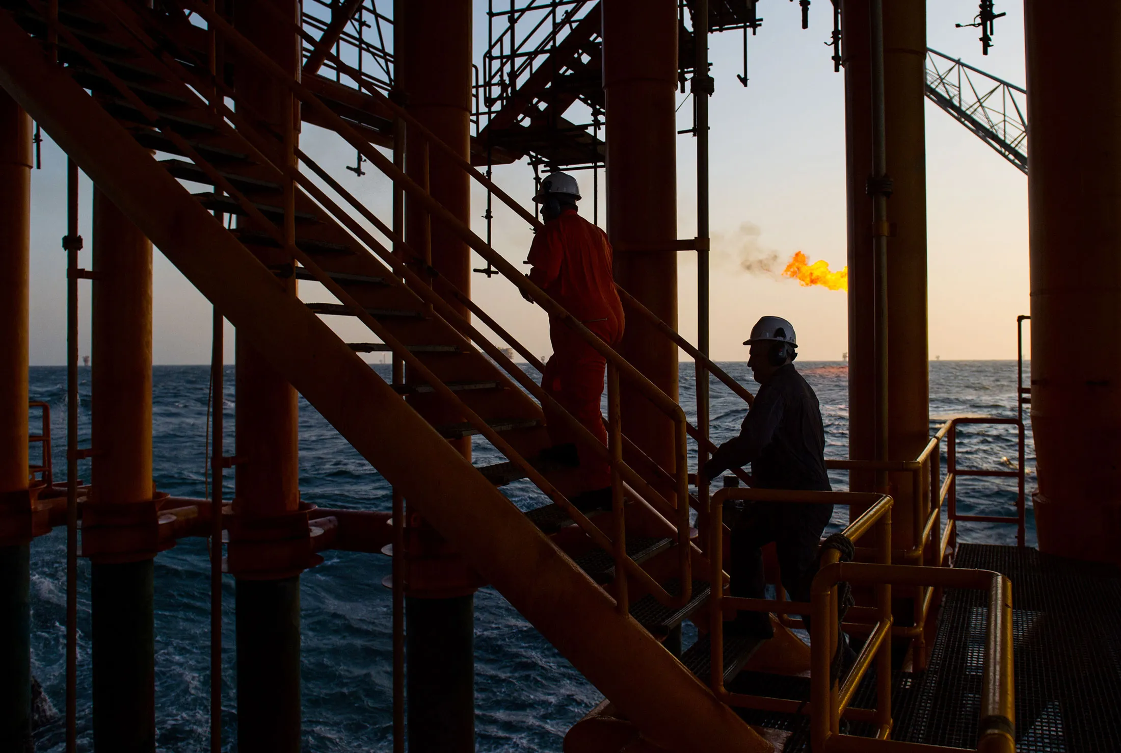 Workers climb stairs from a lower deck aboard an offshore oil platform in the Persian Gulf's Salman Oil Field.