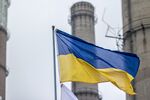 A Ukrainian national flag flies beneath chimneys at the Luhansk thermal power station, operated by DTEK Holdings BV, in Shchastia, Ukraine, on Thursday, March 5, 2015. DTEK, Ukraine's largest privately-owned utility, said it bought coal from South Africa after Russian supplies of the fuel stopped in November. Photographer: Vincent Mundy/Bloomberg
