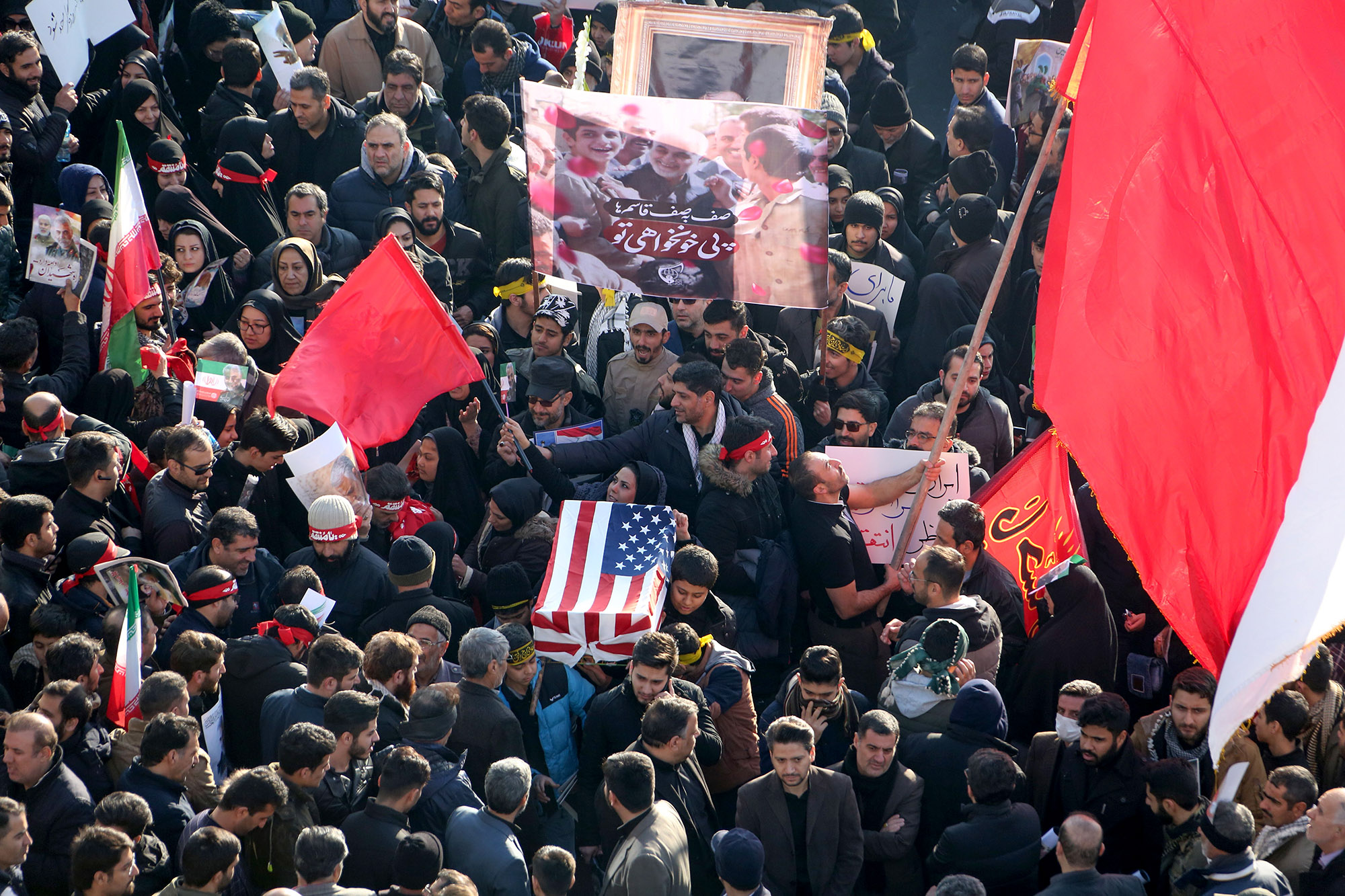 Iranian mourners carry a symbolic coffin wrapped in a U.S. flag during the funeral procession for Qasem Soleimani in Tehran on Jan. 6.