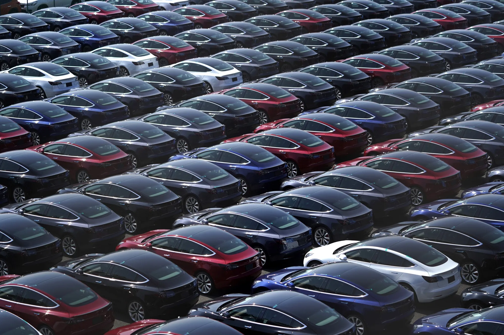 Tesla vehicles sit in a parking lot at a port.