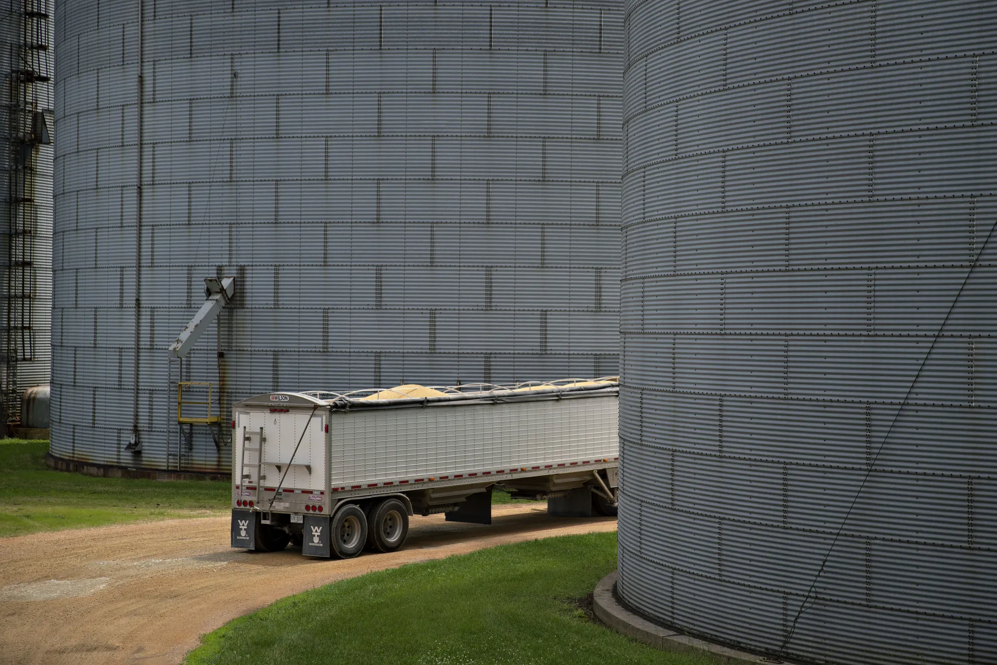 A truck filled with soybeans drives between storage bins at a grain elevator in Ohio, Illinois.