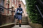 A United States Postal Service (USPS) letter carrier wears a protective mask and gloves while delivering mail in Fairfax, Virginia. 