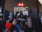 Pedestrians walk past the logo for HSBC outside a local branch bank in Hong Kong.