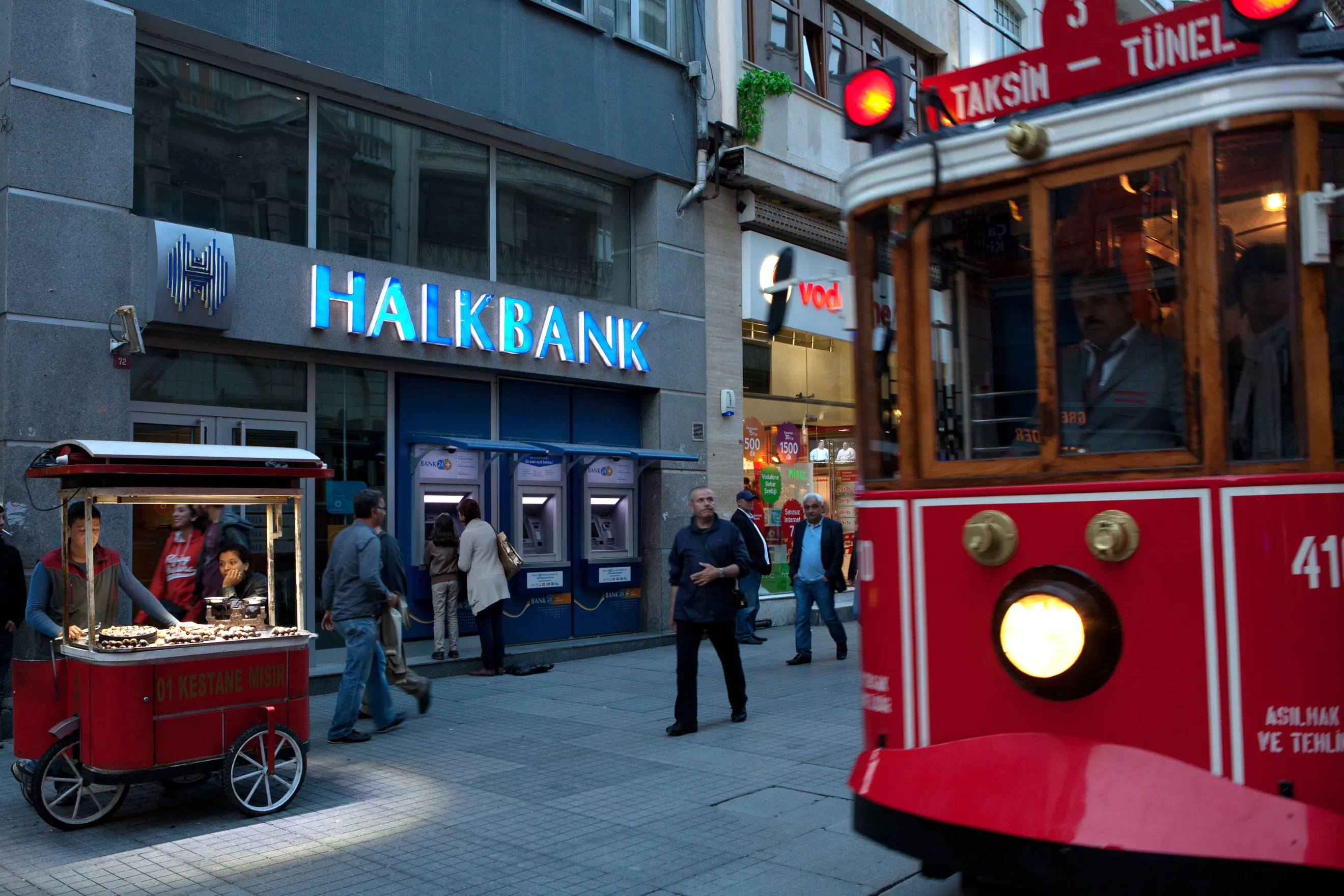 A tram and pedestrians pass a branch of Turkiye Halk Bankasi AS, or Halkbank, in Istanbul, Turkey.