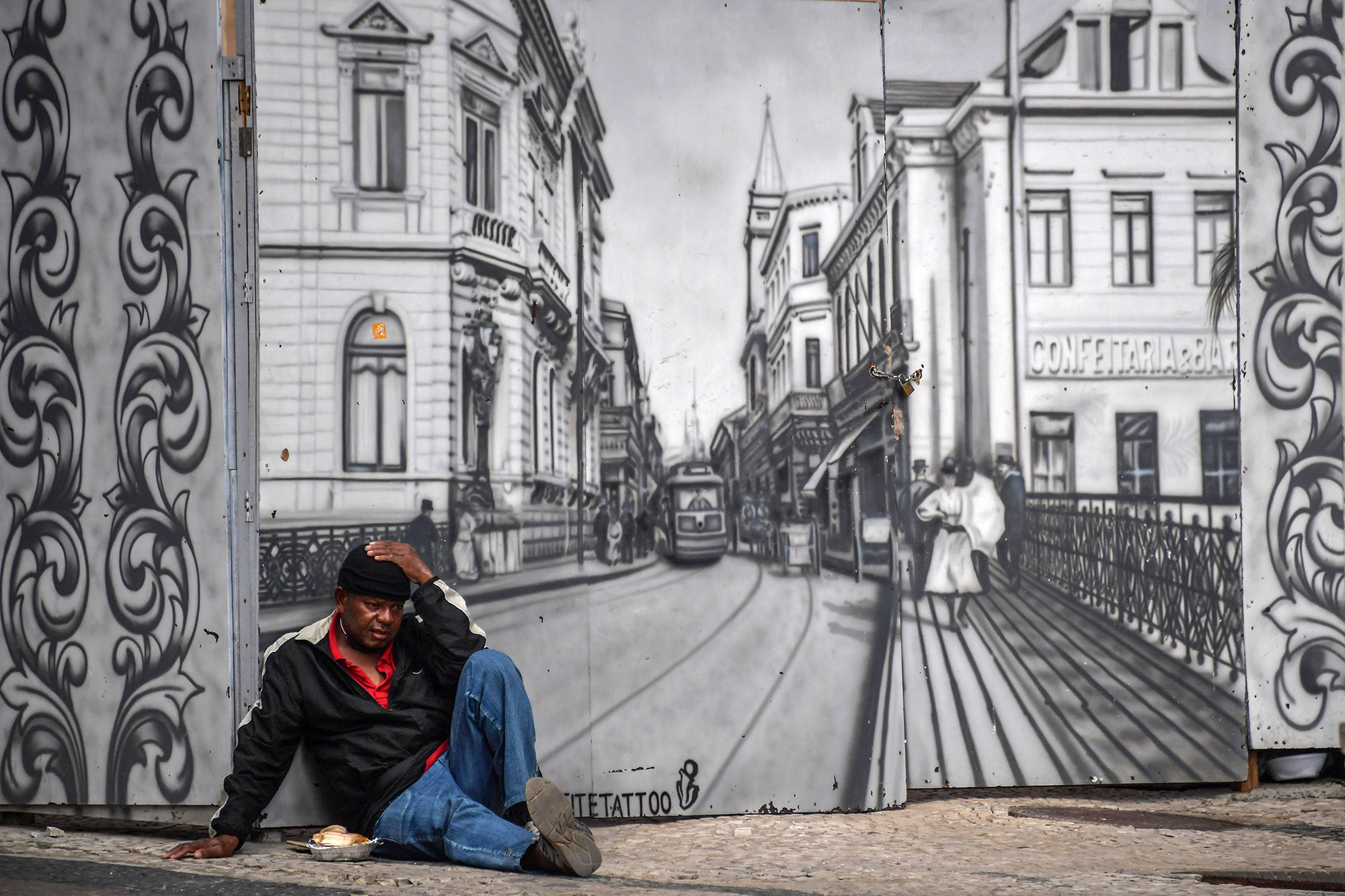 A man begs in front of a mural depicting old Sao Paulo, in Sao Paulo, Brazil, on July 6.