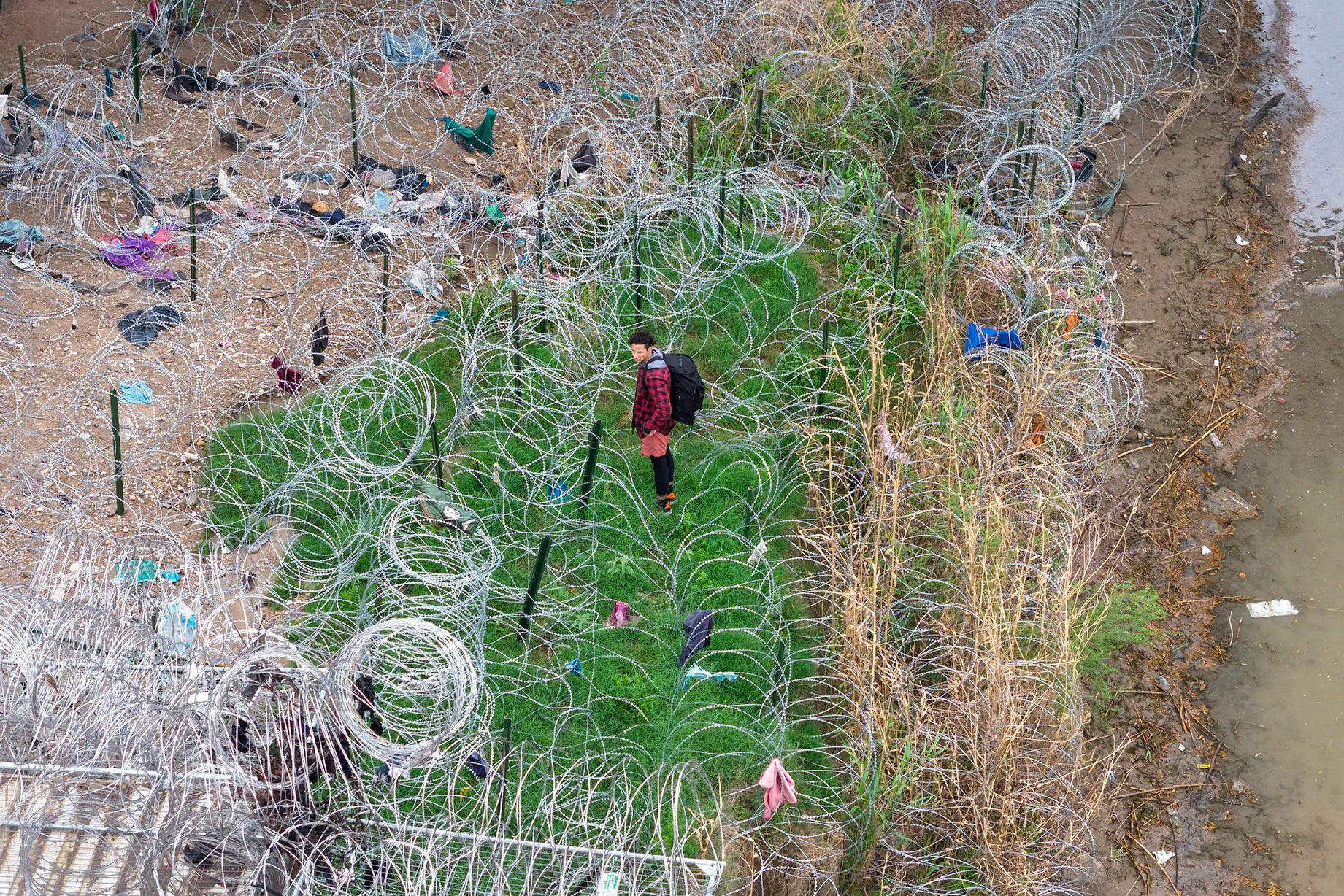 An&nbsp;immigrant faces coils of razor wire after crossing the Rio Grande from Mexico,&nbsp;in Eagle Pass, Texas, on March 17.