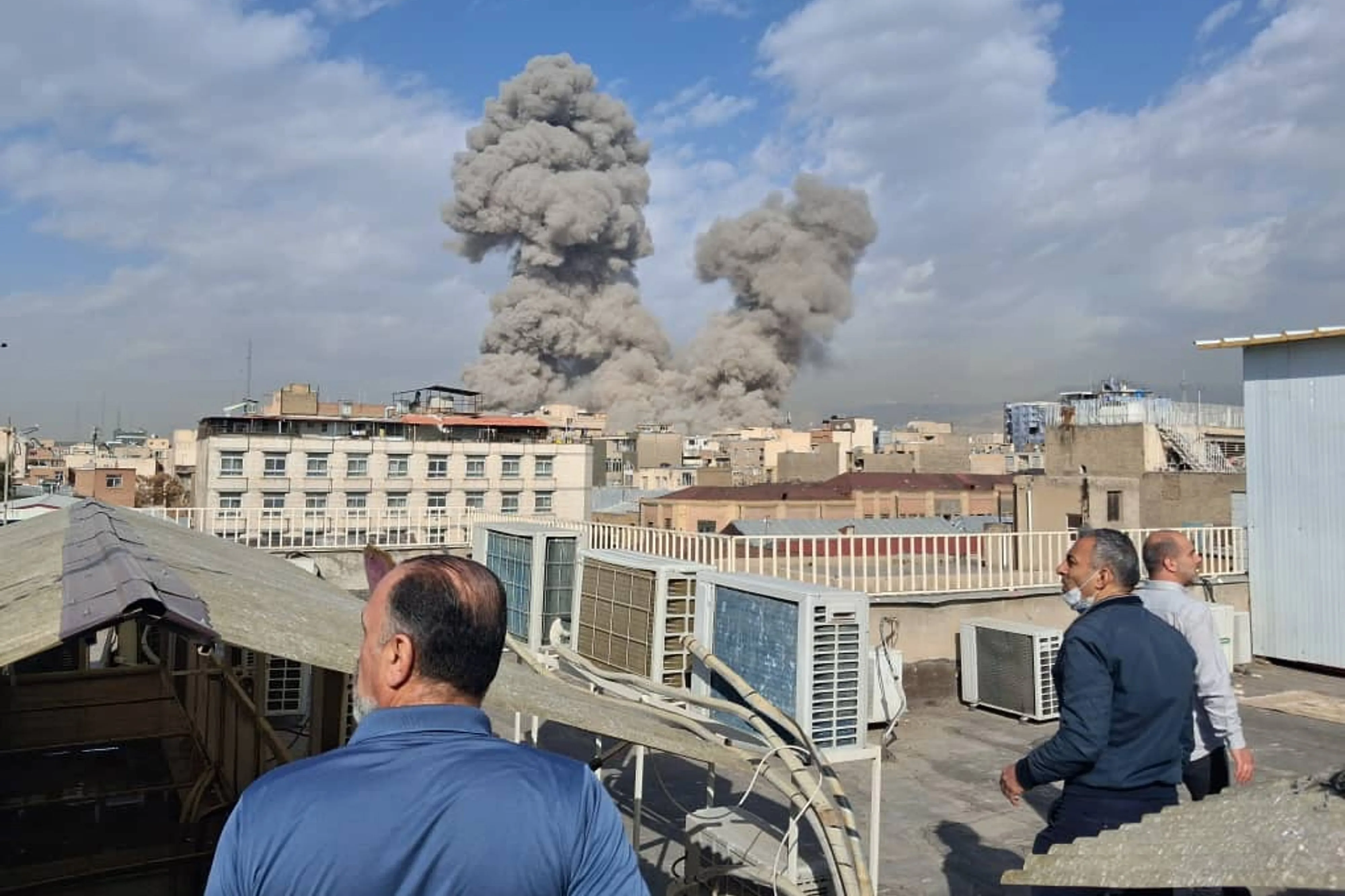 People watch as smoke rises on the skyline after an explosion in Tehran, Iran, on Feb. 28.