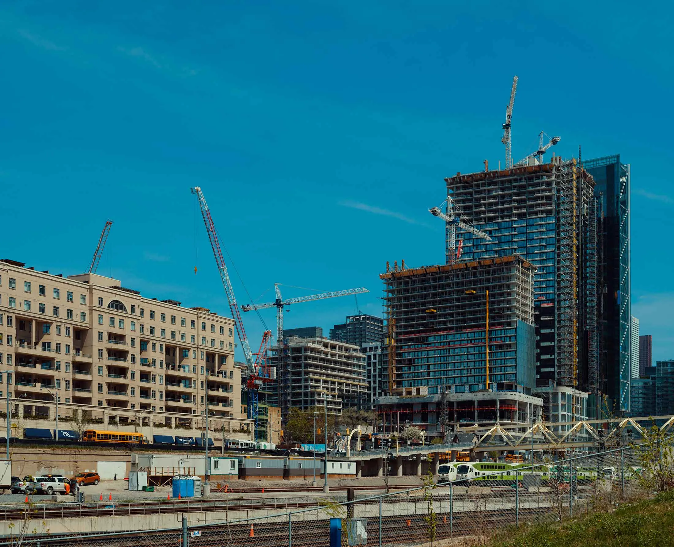 Construction cranes at the Well, a mixed-use development in Toronto that’s near a commuter rail station.