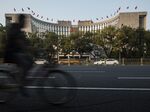 A man rides a bicycle past the People's Bank of China headquarters in Beijing, China, on Monda