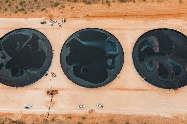 An aerial view of three circular pools of water in a dusty dirt landscape