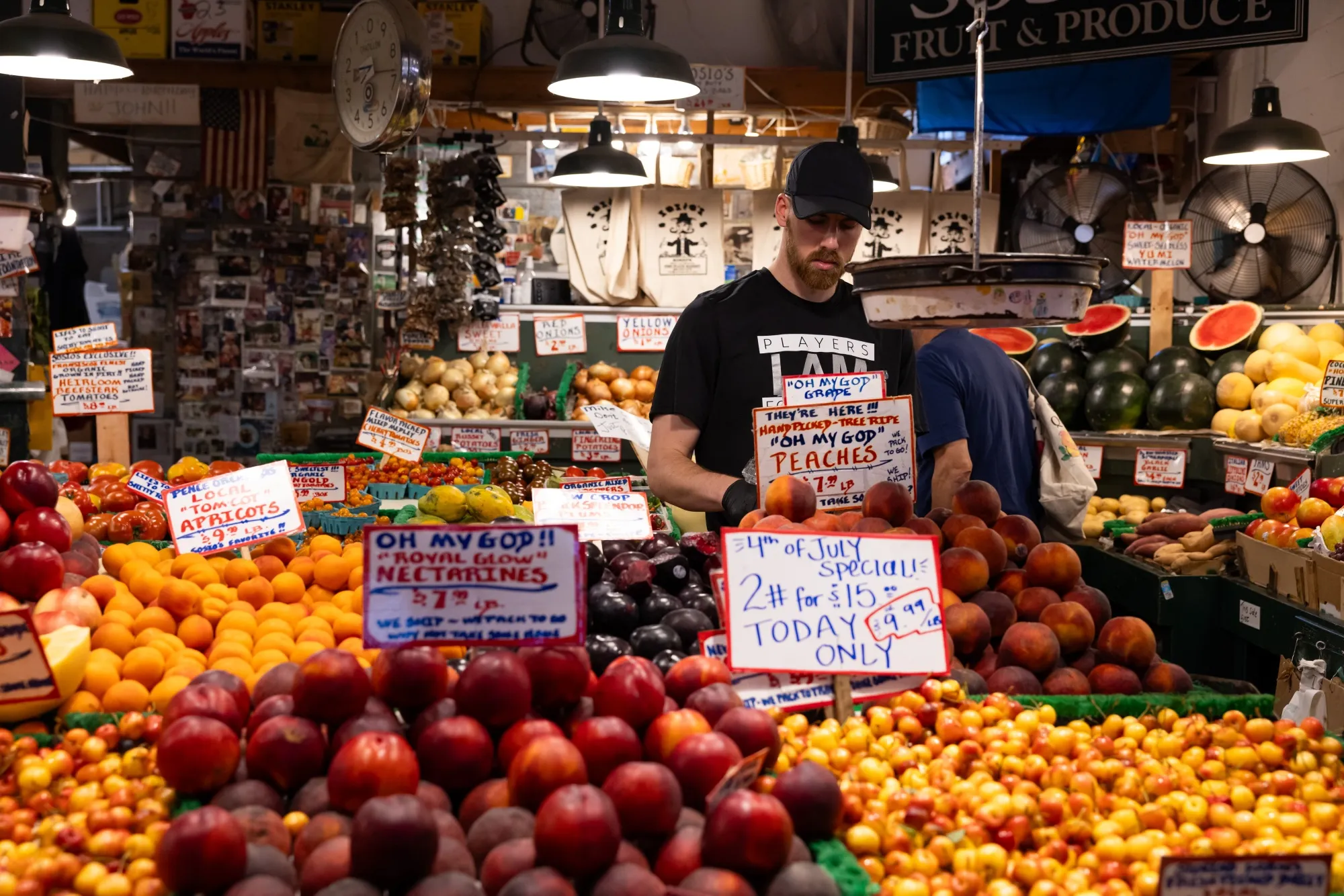 A worker arranges peaches at a fruit stand in the Pike Place Market in Seattle, on July 4. The Bureau of Labor Statistics is scheduled to release US consumer price index figures on July 11.