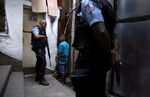 An officer questions a young boy in the Santa Marta slum in Rio de Janeiro, Brazil.