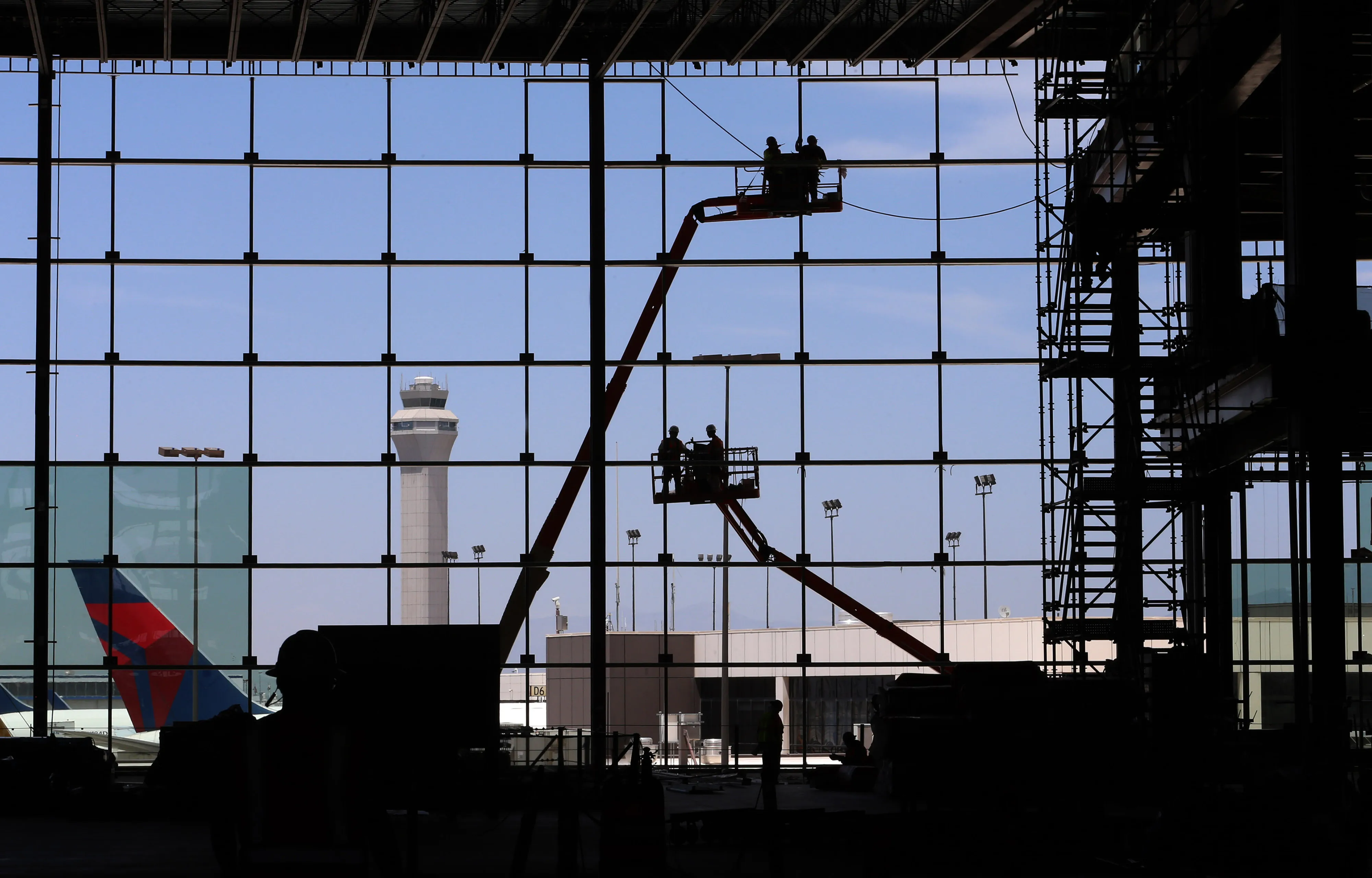 Workers stand in cherry pickers during construction at Salt Lake City International Airport on Thur. June 28, 2018.