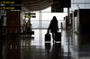 A passenger wheels a suitcase through a deserted arrivals hall at Madrid Barajas airport, in Madrid.