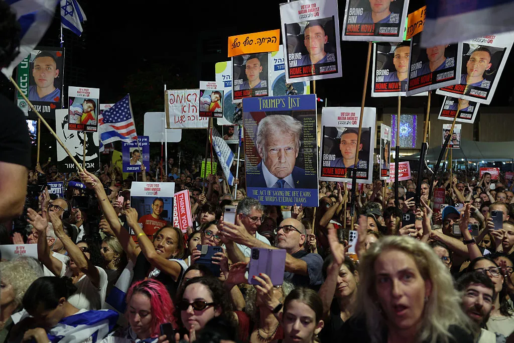 People hold images of hostages and Donald Trump at Hostages Square in Tel Aviv on Oct. 11.