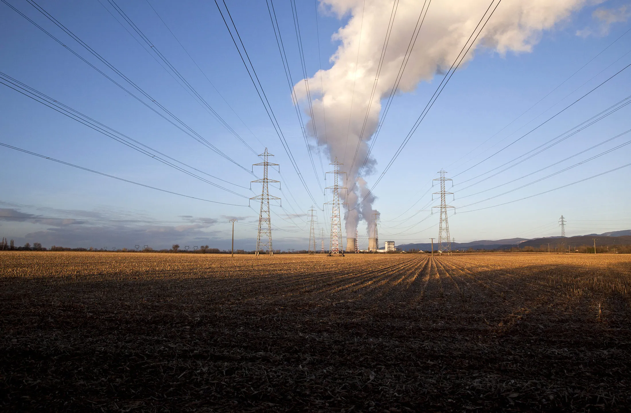Power transmission lines hang from electricity pylons as the cooling towers of Electricite de France SA's (EDF) nuclear power plant emit vapor in Bugey, France, on Sunday, Jan. 5, 2014. EDF's deal with the U.K. to build the nation's first new nuclear plant in two decades faces an in-depth investigation by the European Union, which must approve large state subsidies.
