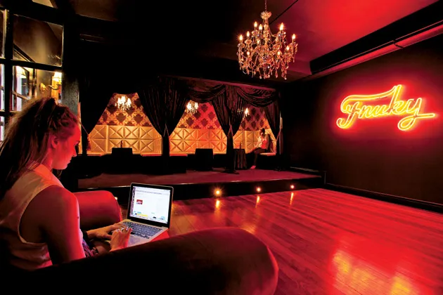 Erica Brien, a Fnuky employee, surfs the Web from a vintage club chair in the bar in the entrance foyer