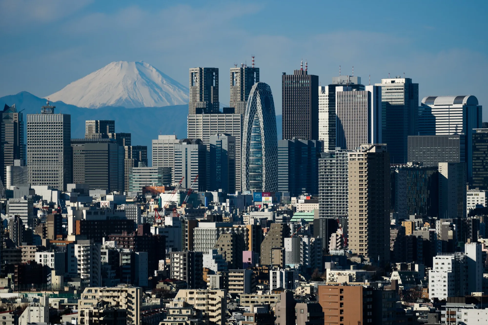 Mount Fuji stands beyond buildings in Tokyo, Japan.