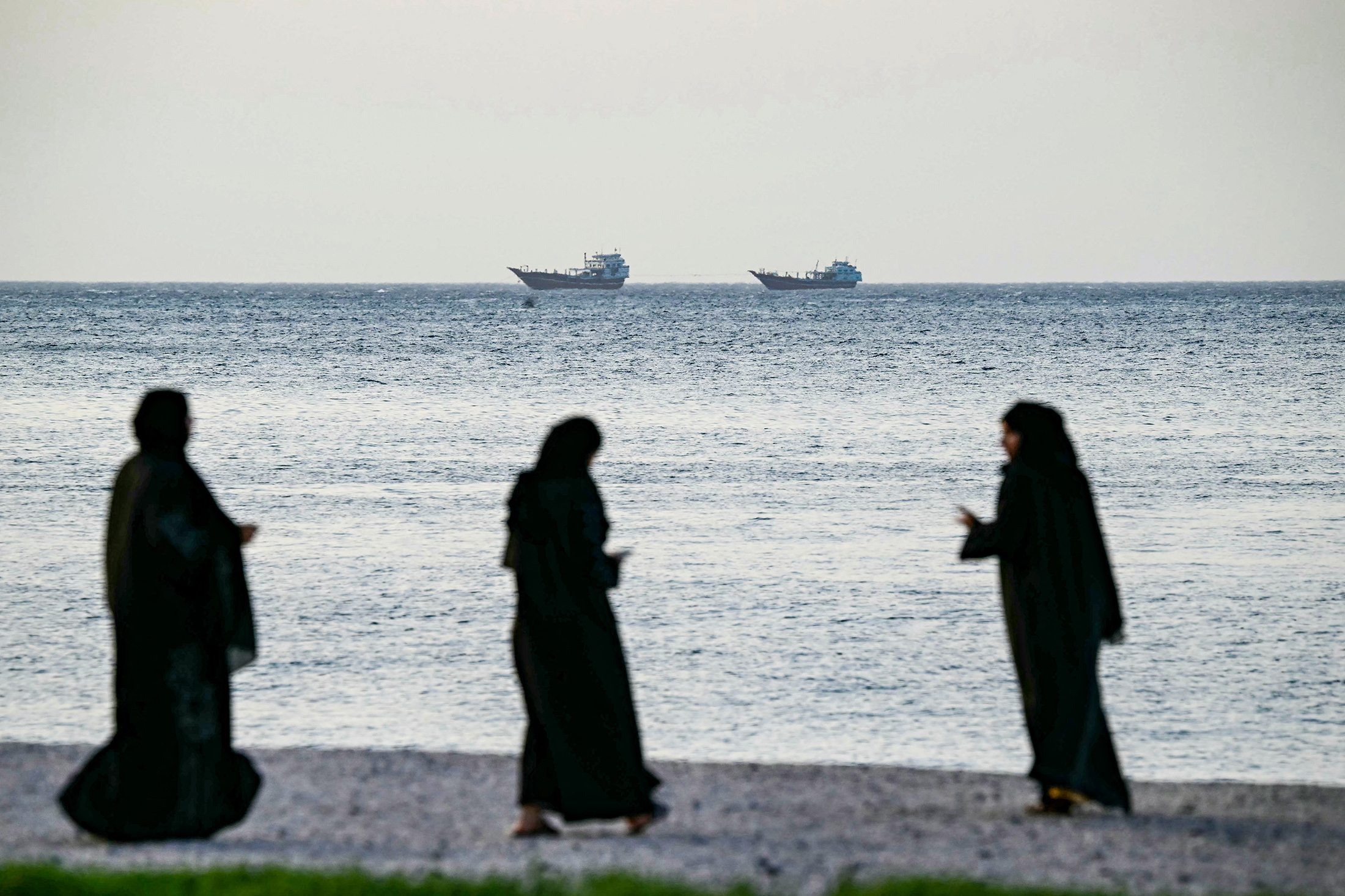 Women walk on a beach in Khasab, on northern Oman's Musandam Peninsula, overlooking the Strait of Hormuz on June 24, 2025. Photographer: Giuseppe Cacace/AFP/Getty Images