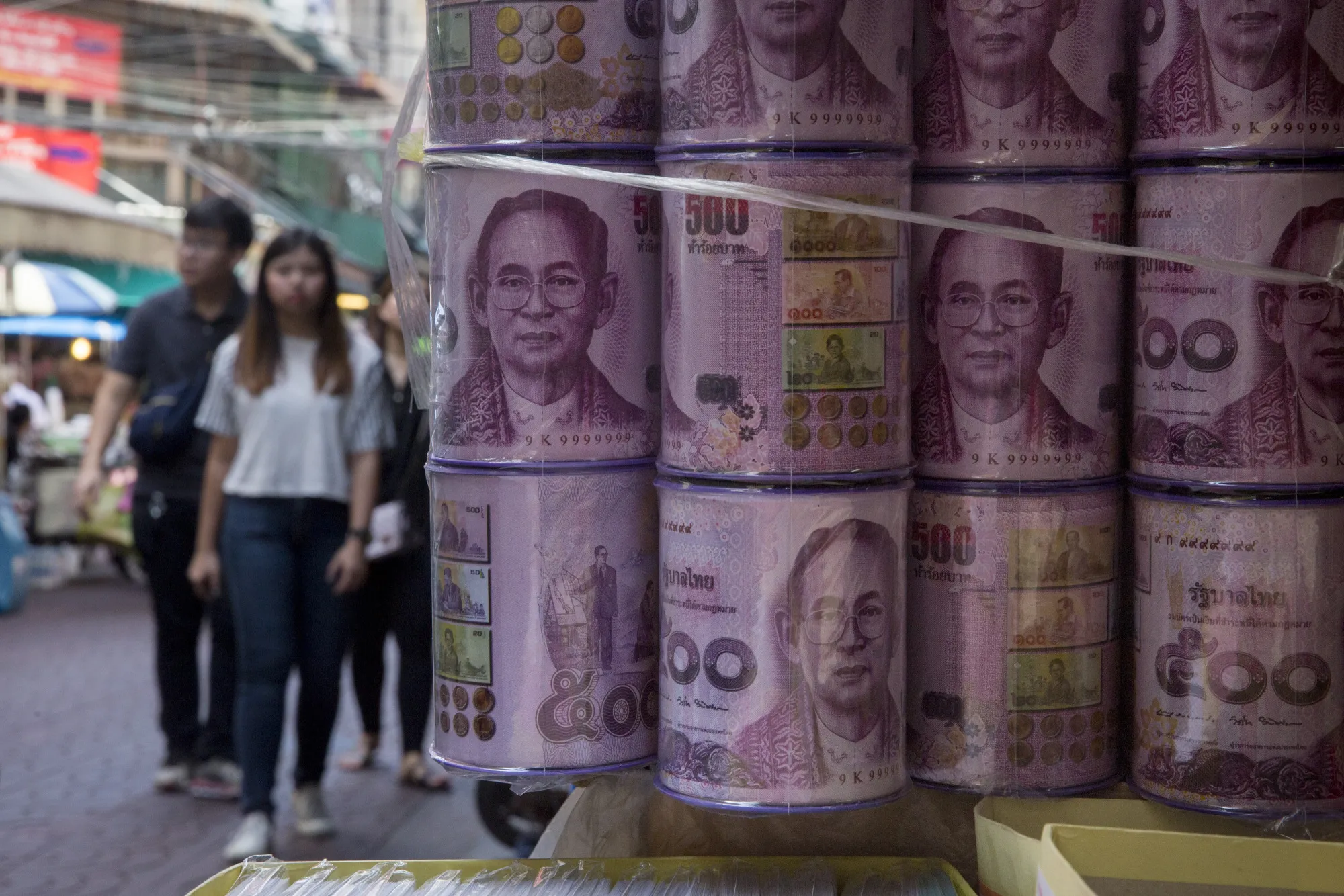 Storage cans designed with Thai 50 baht banknotes featuring portraits of the late Thai King Bhumibol Adulyadej are displayed for sale at a stall in Bangkok, Thailand.
