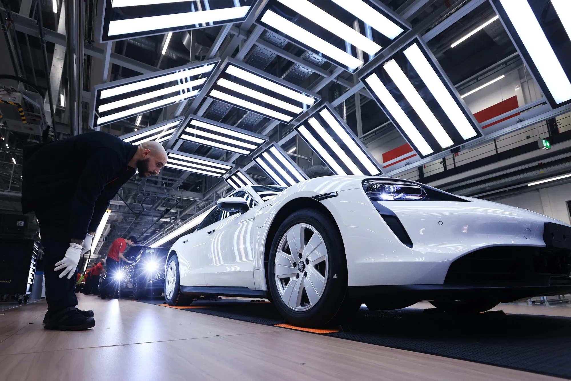 Employees check all-electric Taycan automobiles on the production line at the Porsche AG factory in Stuttgart, Germany.
