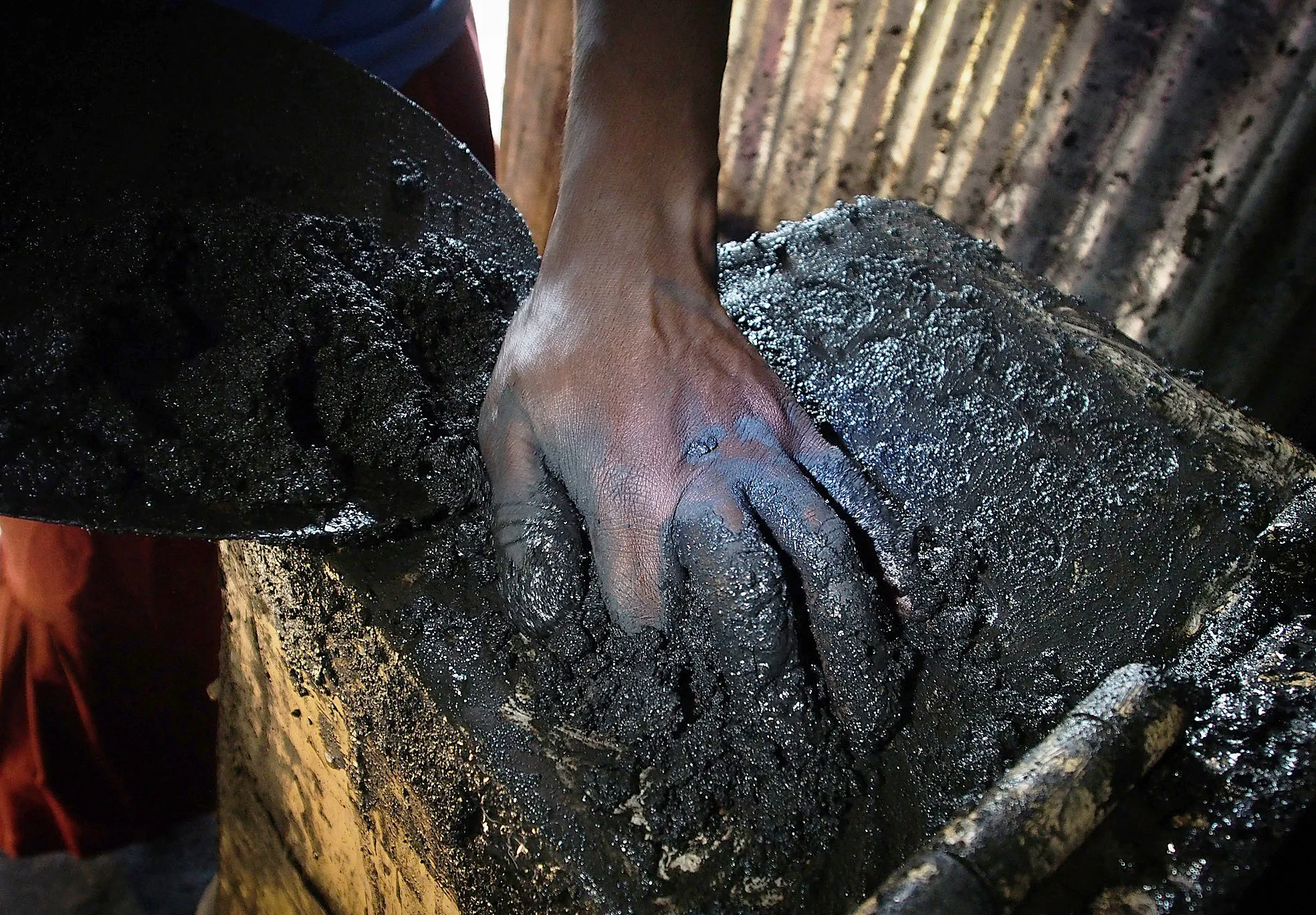 A worker fills a press machine with biochar.