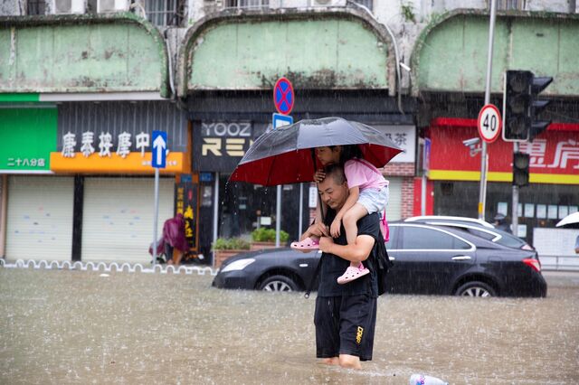 A man carrying his child wades through floodwater on a flooded road in Panyu District of Guangzhou, south China's Guangdong Province, Sept. 8, 2023.