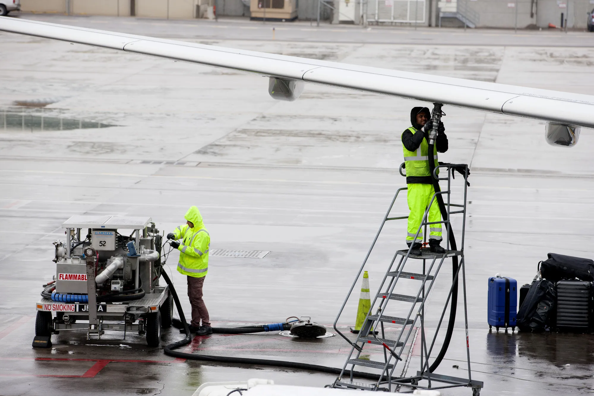 Ground operations employees fuel a plane on the tarmac at Denver International Airport.
